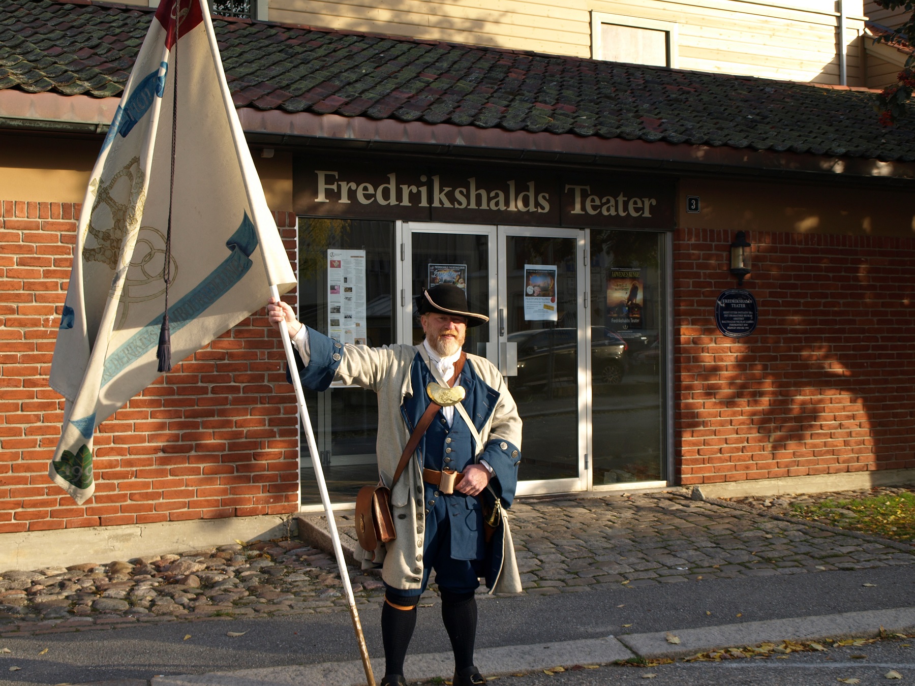 Ivar Mehren med fanen fra Kong Frederik IVs Tambourafdeling af 1704 ønsket velkommen til seminar. Foto: Bodil Andersson, Østfoldmuseene Halden historiske Samlinger