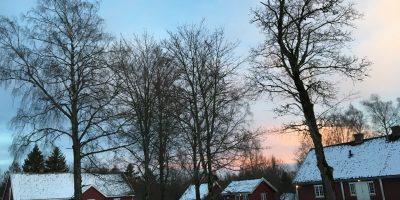 Tre eldre hus i vinterlandskap, trær og himmel